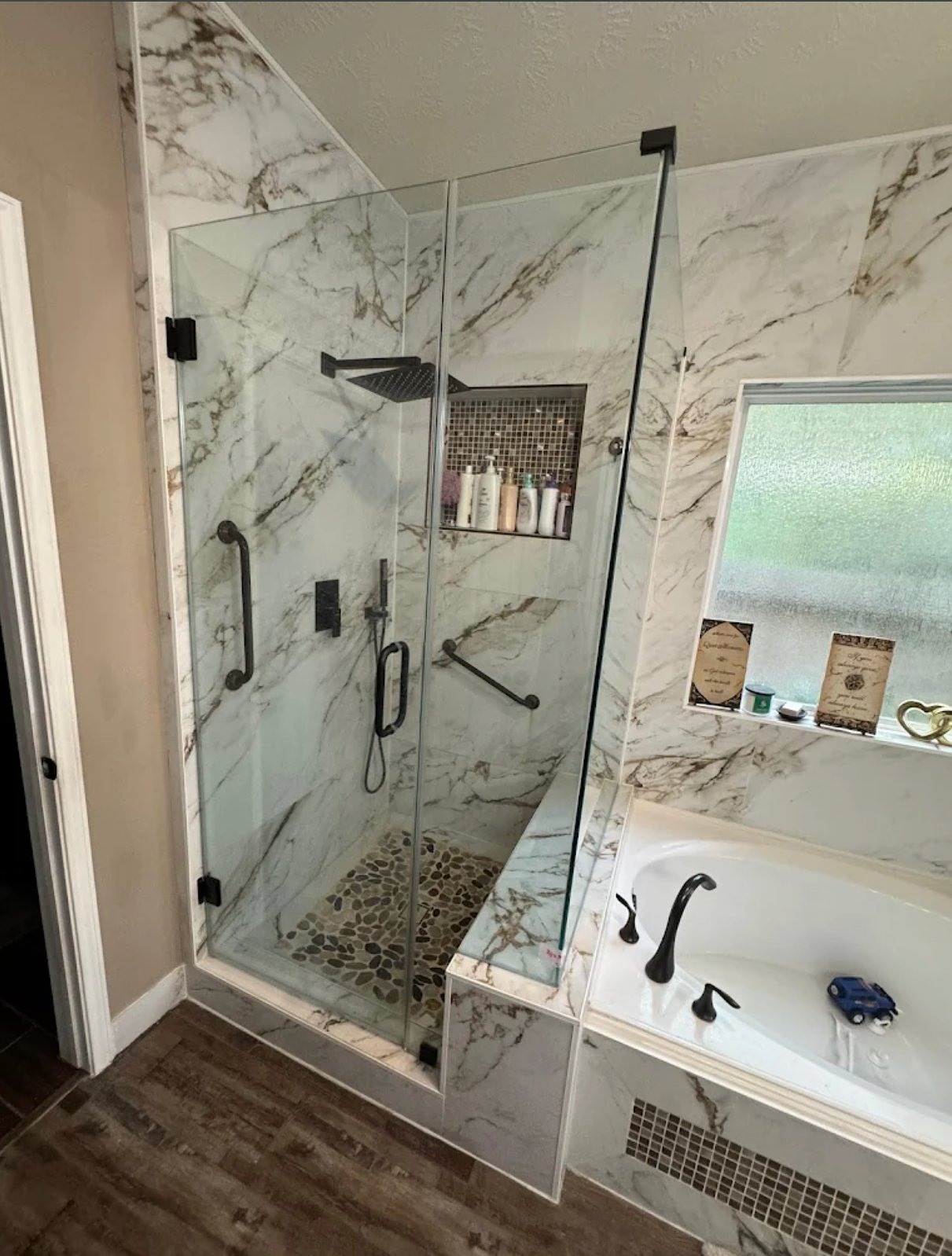Luxurious bathroom with marble-tiled walk-in shower, glass enclosure, rainfall showerhead, and soaking tub