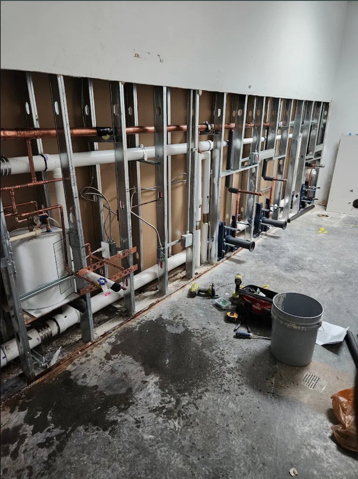 Commercial plumbing installation with multiple water heater units and copper piping systems under construction