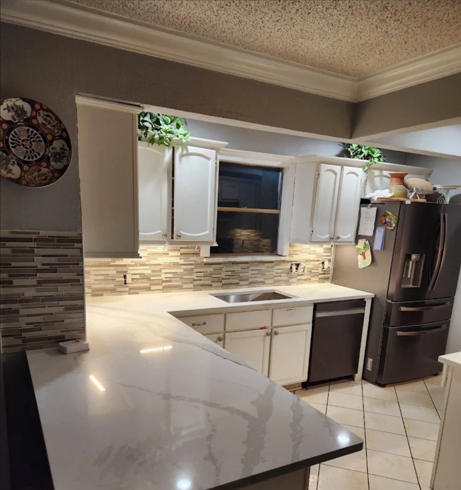 Modern kitchen with white cabinets, marble countertops, stainless steel appliances, and tile backsplash
