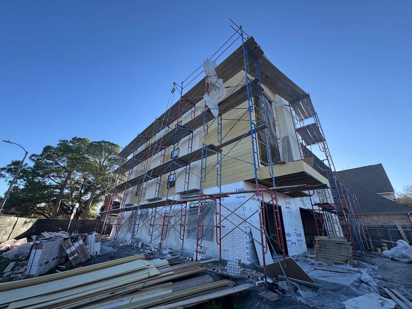Construction site with multi-story residential building under scaffolding and exterior work